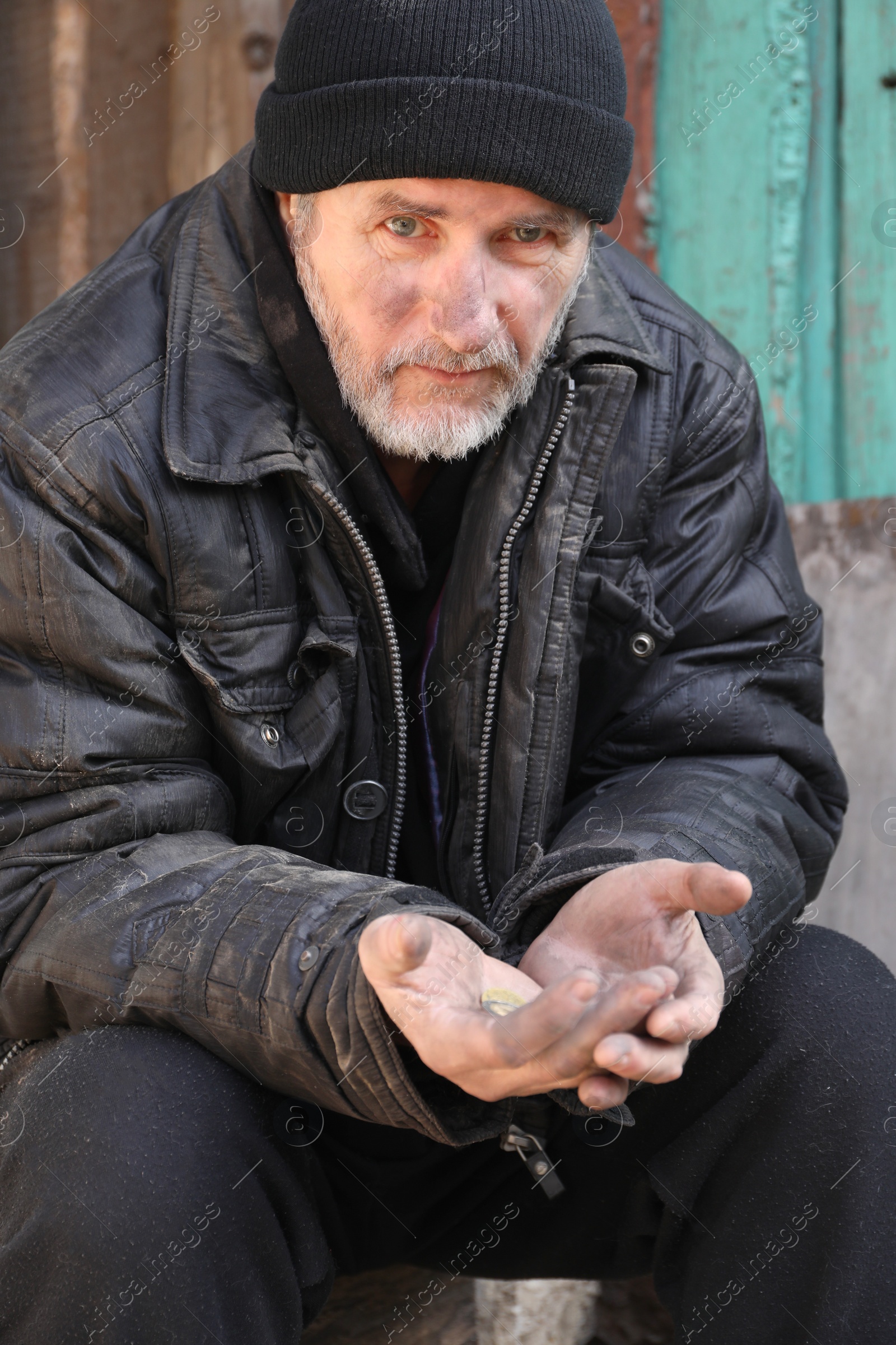 Photo of Poor homeless senior man holding coins outdoors