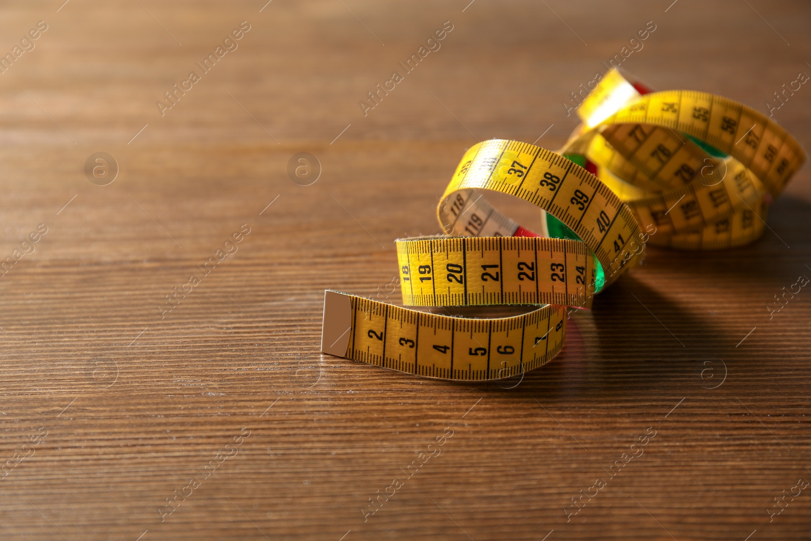 Photo of Measuring tape for tailoring on wooden background