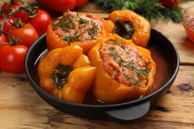 Photo of Tasty stuffed peppers in pan on wooden table, closeup