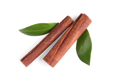 Photo of Cinnamon sticks and green leaves isolated on white, top view