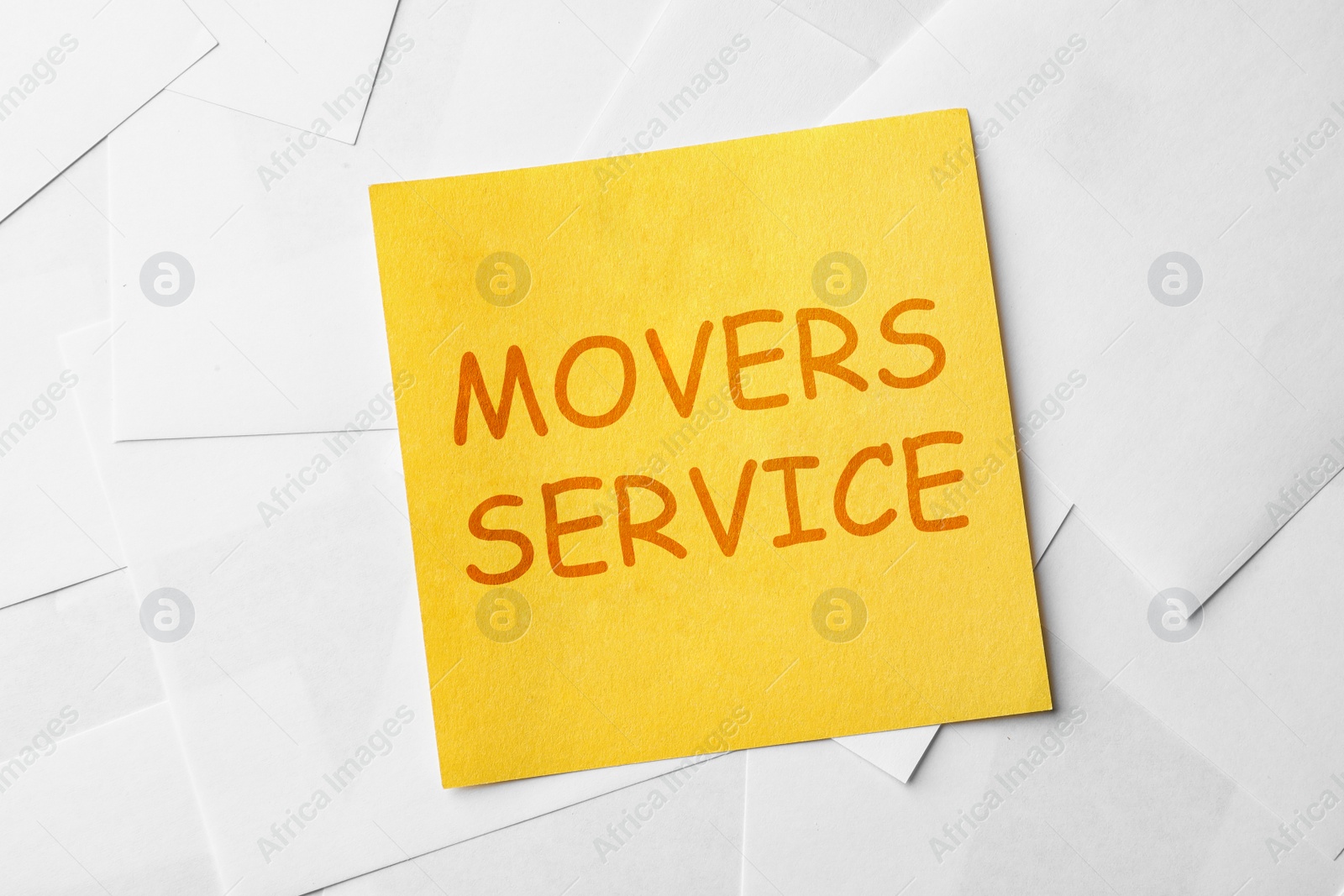 Image of Note with phrase MOVERS SERVICE on paper sheets, top view