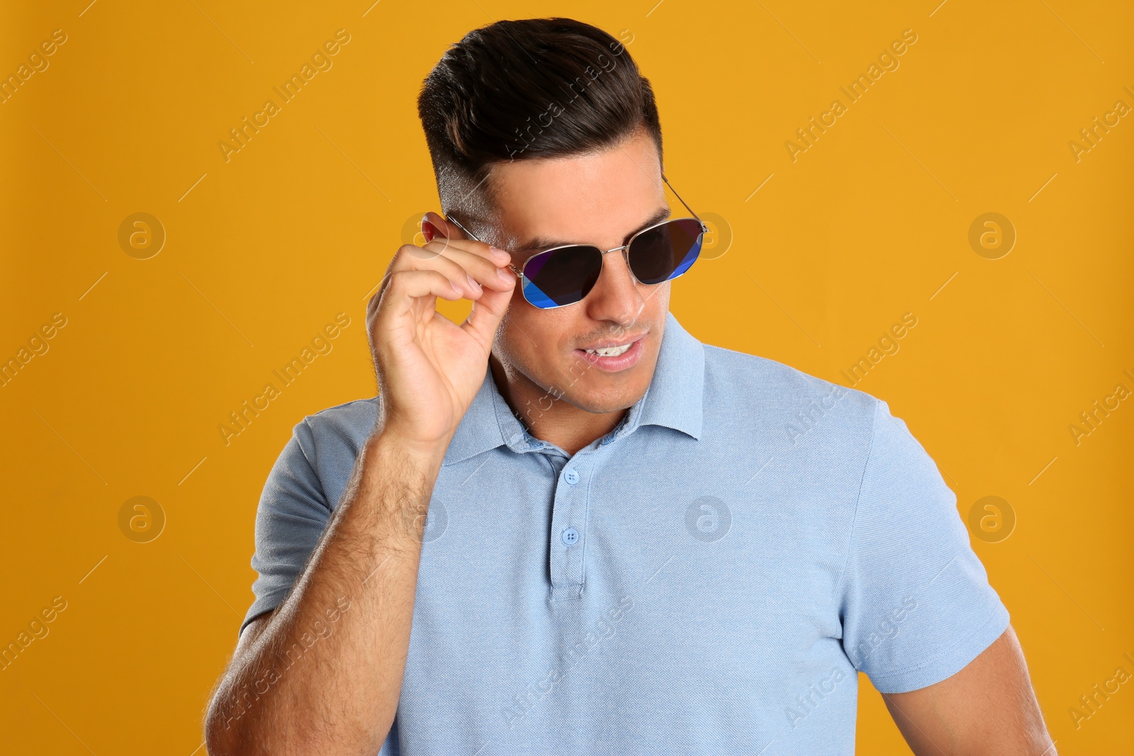 Photo of Handsome man wearing sunglasses on yellow background