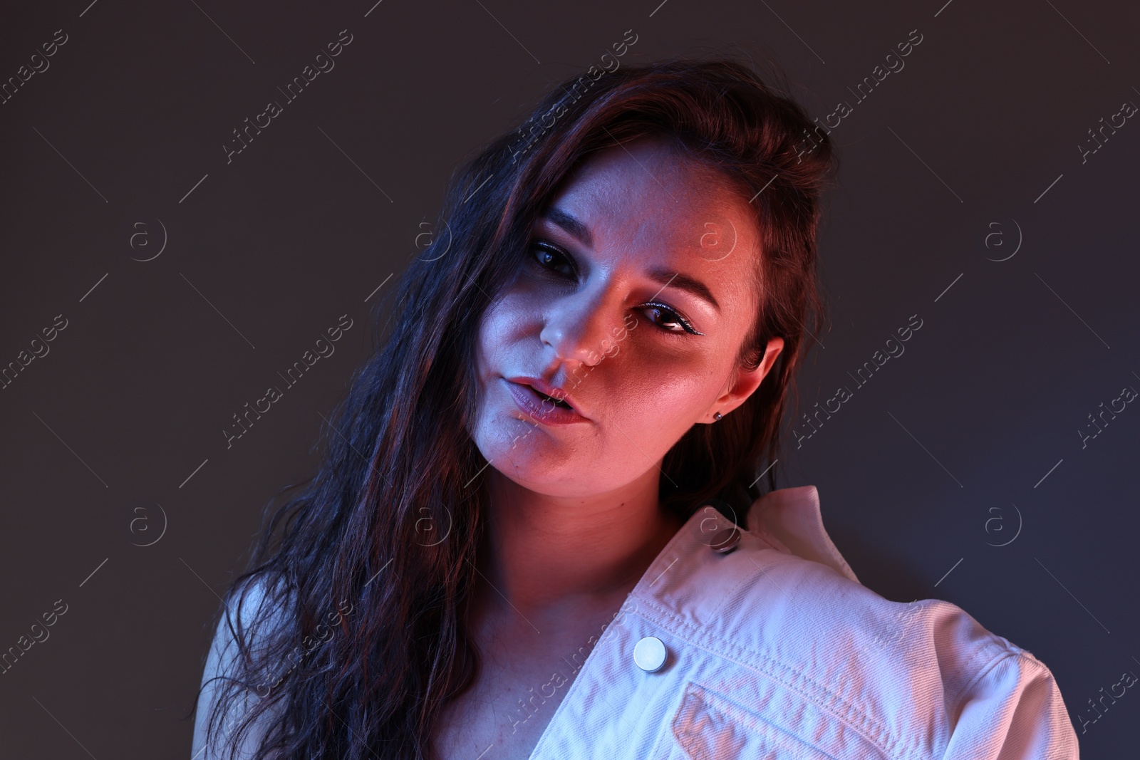 Photo of Portrait of beautiful young woman on color background with neon lights