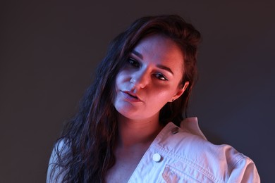 Portrait of beautiful young woman on color background with neon lights