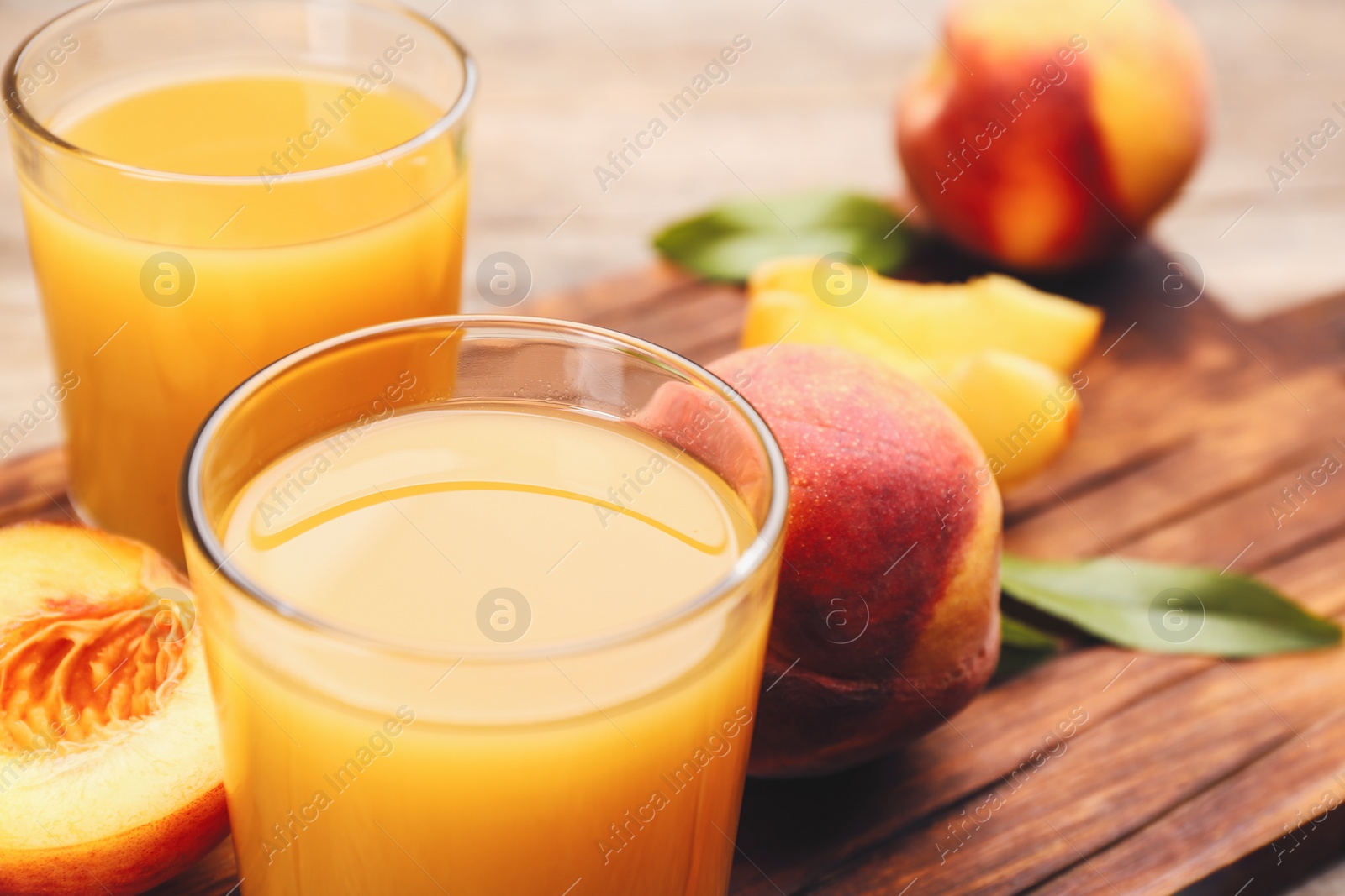 Photo of Natural peach juice and fresh fruits on wooden board, closeup