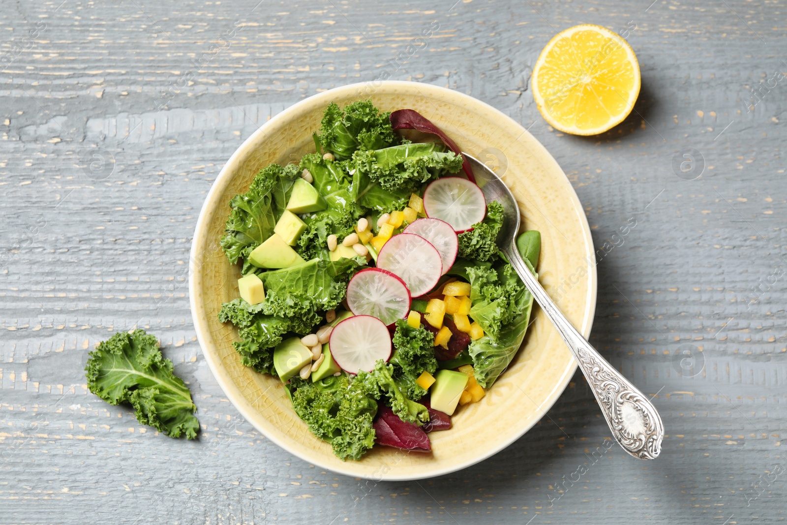 Photo of Delicious kale salad served on grey wooden table, flat lay