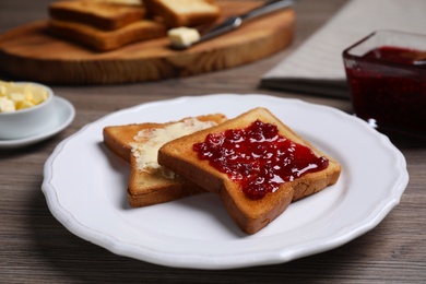 Photo of Fresh toast with jam and butter served on wooden table, closeup