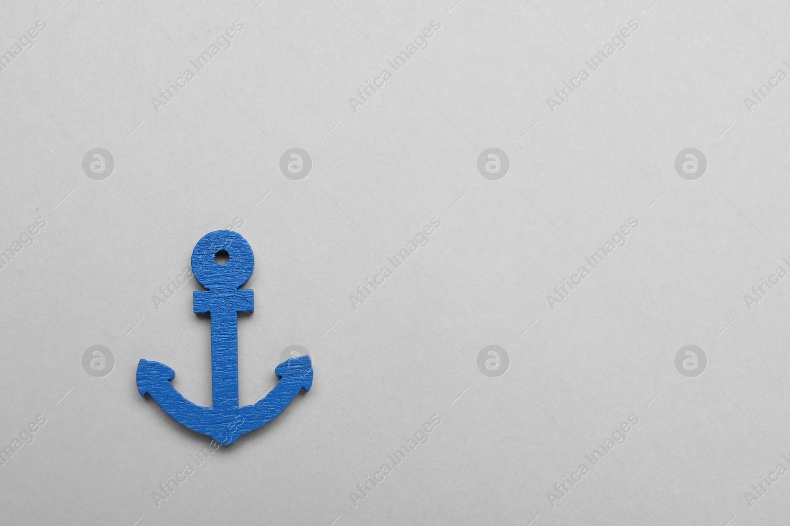 Photo of Anchor figure on light grey background, top view. Space for text