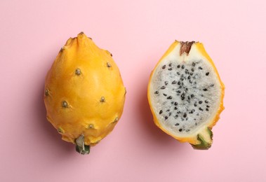 Delicious cut and whole dragon fruits (pitahaya) on pink background, flat lay