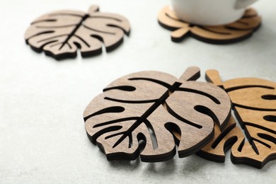 Leaf shaped wooden cup coasters on white table