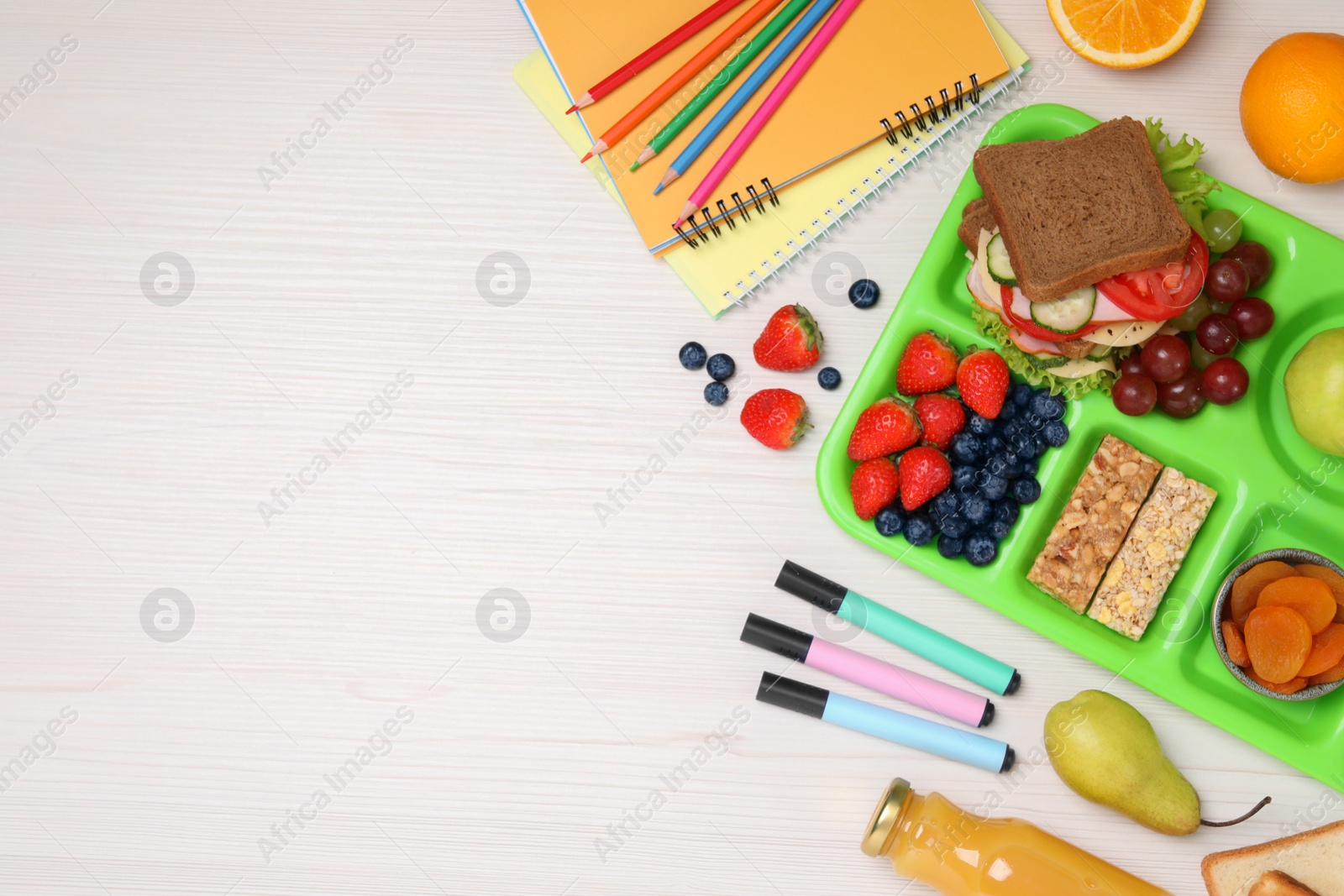 Photo of Serving tray of healthy food, stationery and space for text on white wooden table, flat lay. School lunch