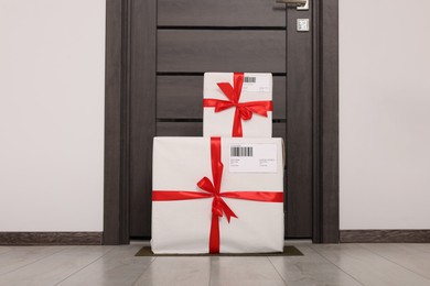 Photo of Christmas gift boxes on floor near door. Sending present by mail