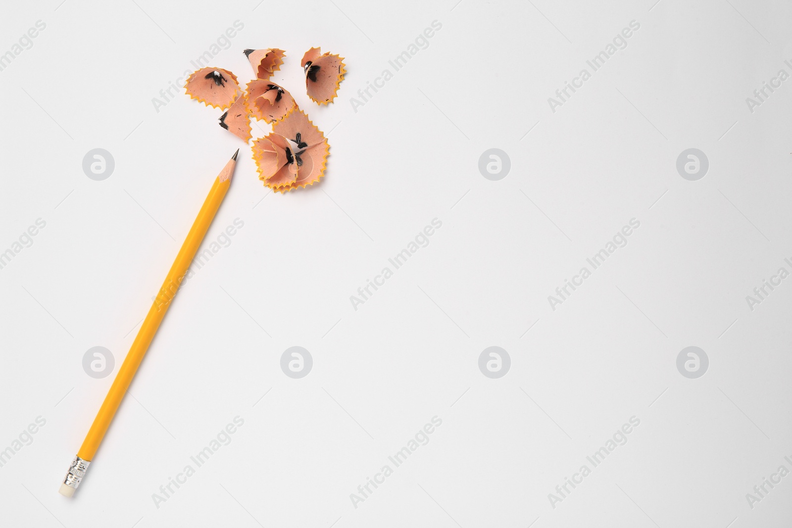 Photo of Sharp graphite pencil and shavings on white background, top view. Space for text