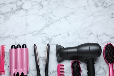 Flat lay composition of professional hairdresser tools on white marble table, space for text