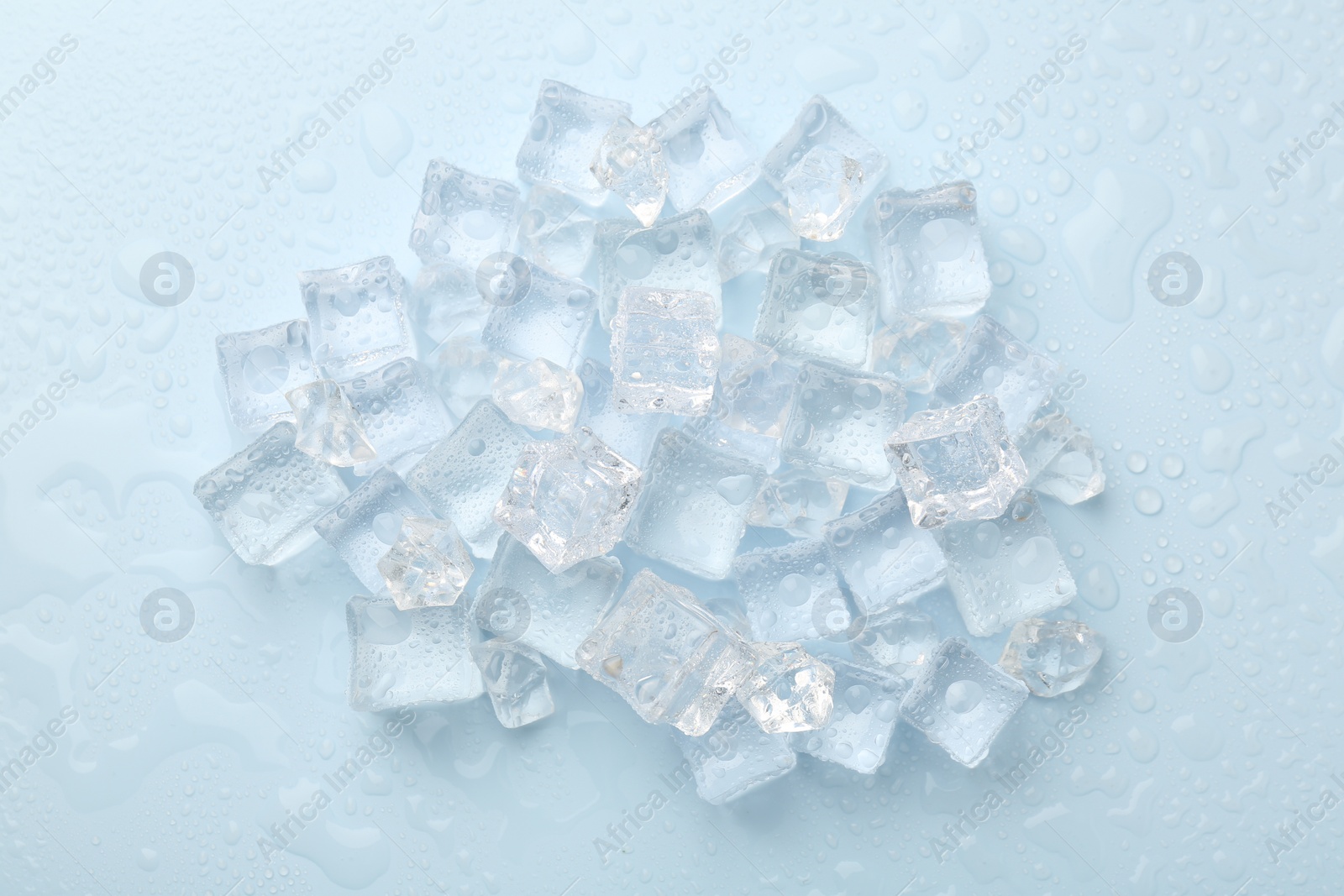 Photo of Crystal clear ice cubes on light blue background, flat lay