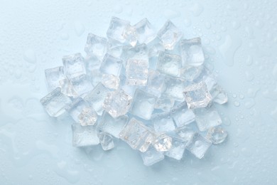 Crystal clear ice cubes on light blue background, flat lay