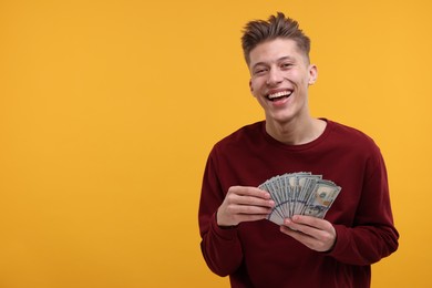 Photo of Happy man with dollar banknotes on yellow background. Space for text