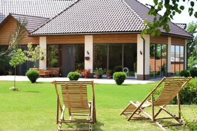 Wooden deck chairs in beautiful garden on sunny day