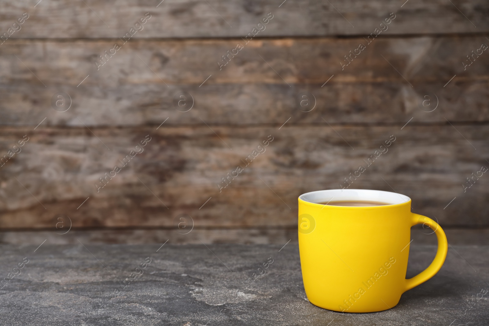 Photo of Yellow ceramic cup with hot aromatic coffee on table