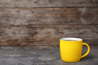 Yellow ceramic cup with hot aromatic coffee on table