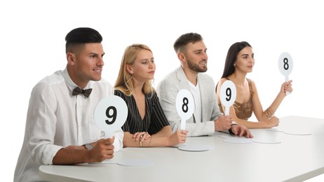 Panel of judges holding different score signs at table on white background