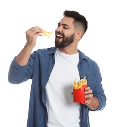 Young man eating French fries on white background