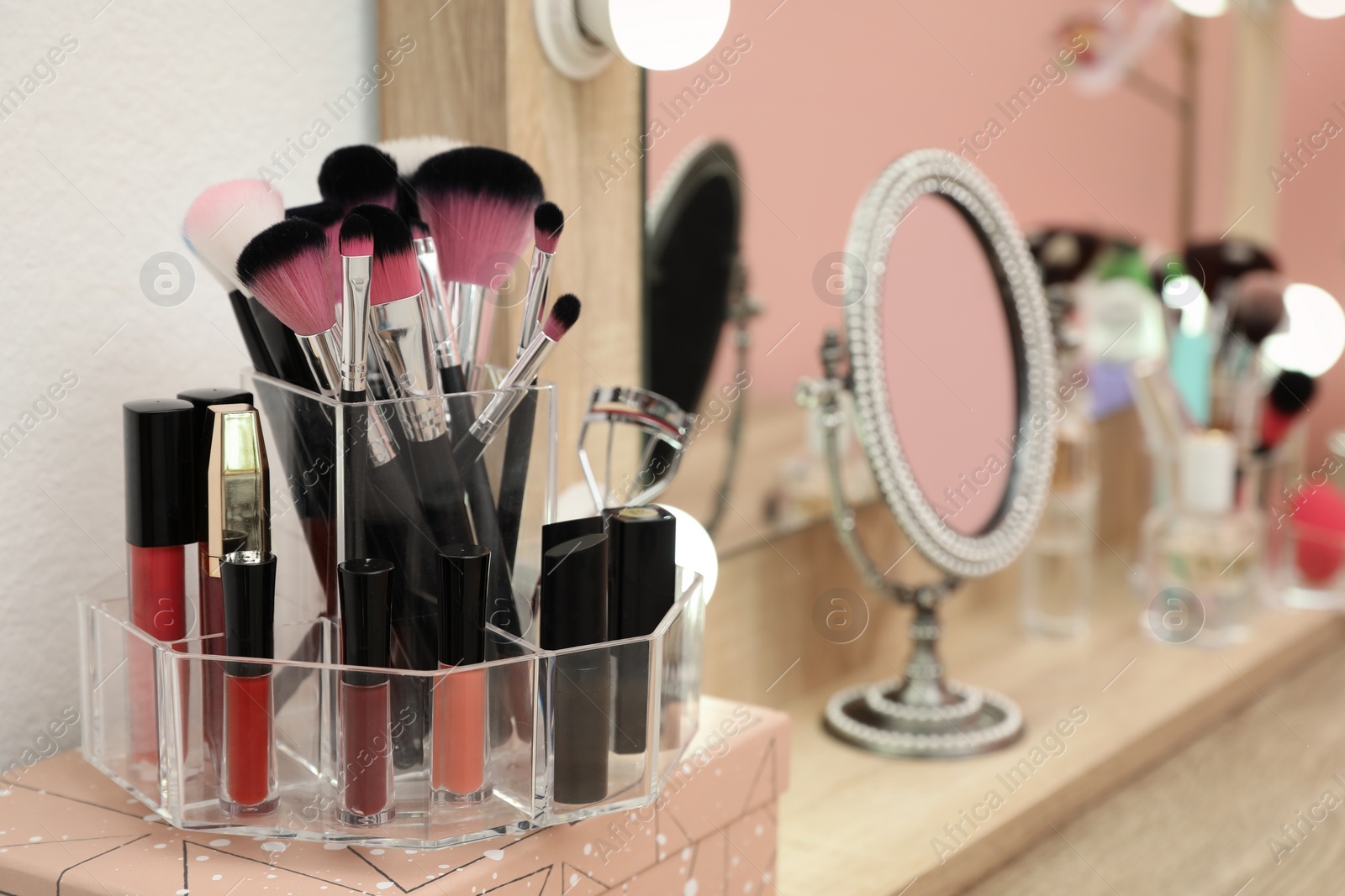 Photo of Organizer with cosmetic products for makeup on table near mirror. Space for text