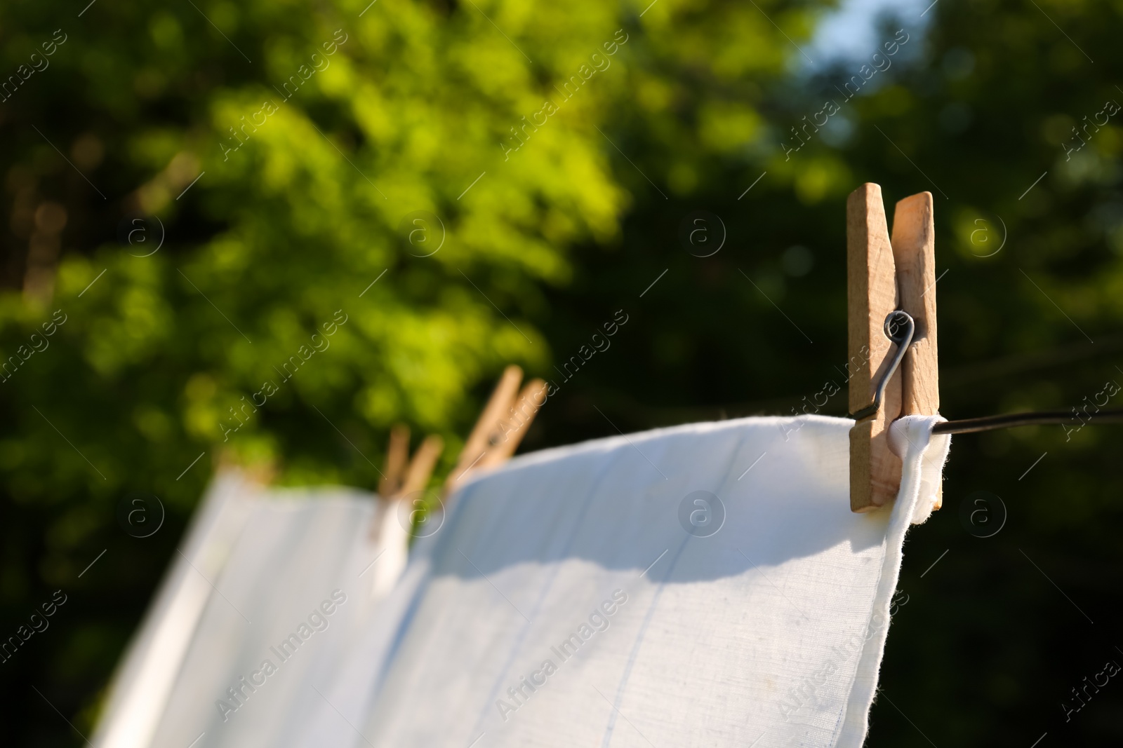 Photo of Washing line with clean laundry and clothespins outdoors, closeup