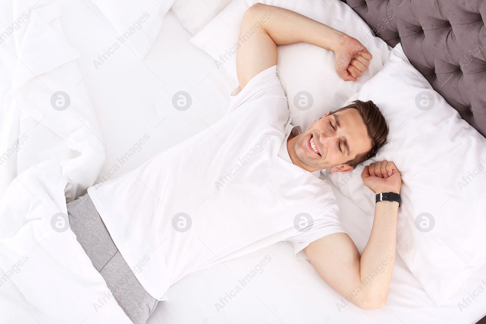 Photo of Young man after sleeping in bed at home, top view