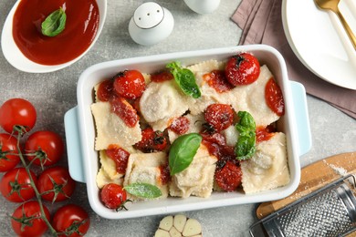 Tasty ravioli with tomato sauce served on grey table, flat lay