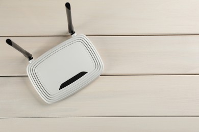 Photo of Modern Wi-Fi router on white wooden background, top view. Space for text