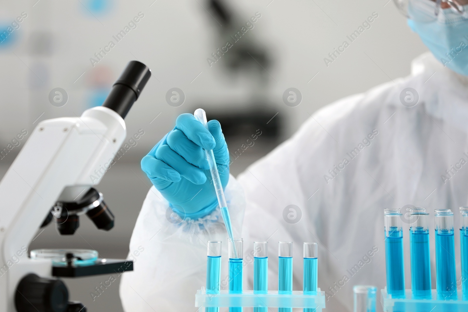 Photo of Scientist dripping sample into test tube in laboratory, closeup