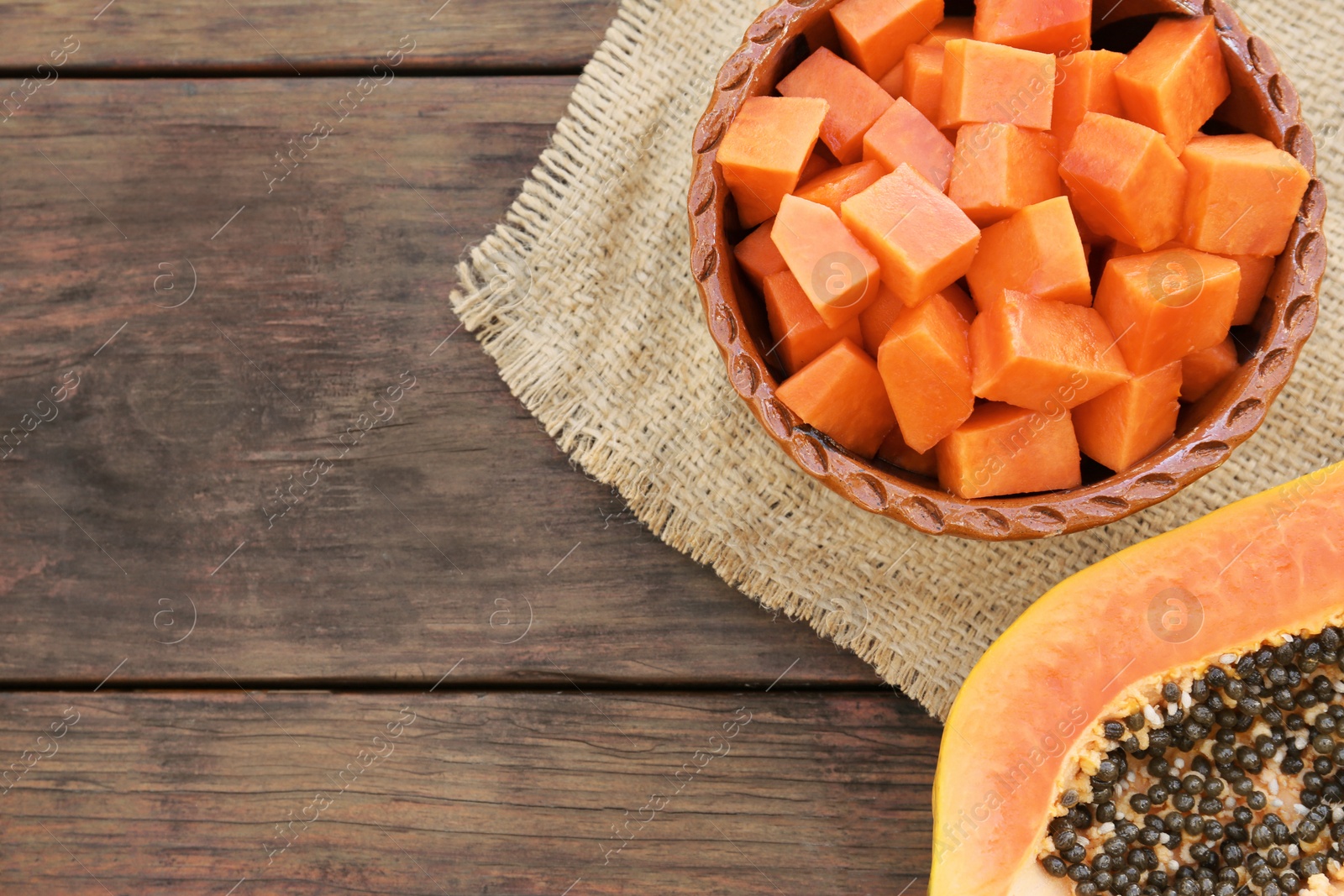 Photo of Tasty ripe cut papaya fruits on wooden table, flat lay. Space for text