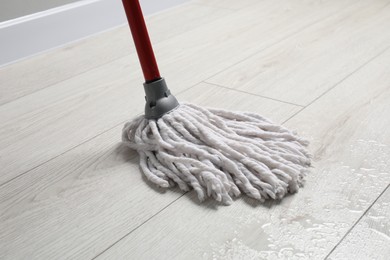 Cleaning dirty wooden floor with mop indoors