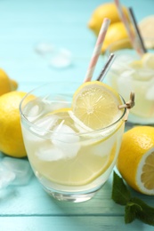 Photo of Natural lemonade on light blue wooden table, closeup. Summer refreshing drink