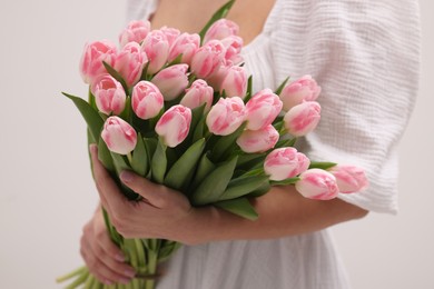 Photo of Woman with bouquet of beautiful fresh tulips on light grey background, closeup
