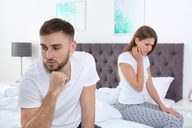 Photo of Young couple with relationship problems ignoring each other in bedroom