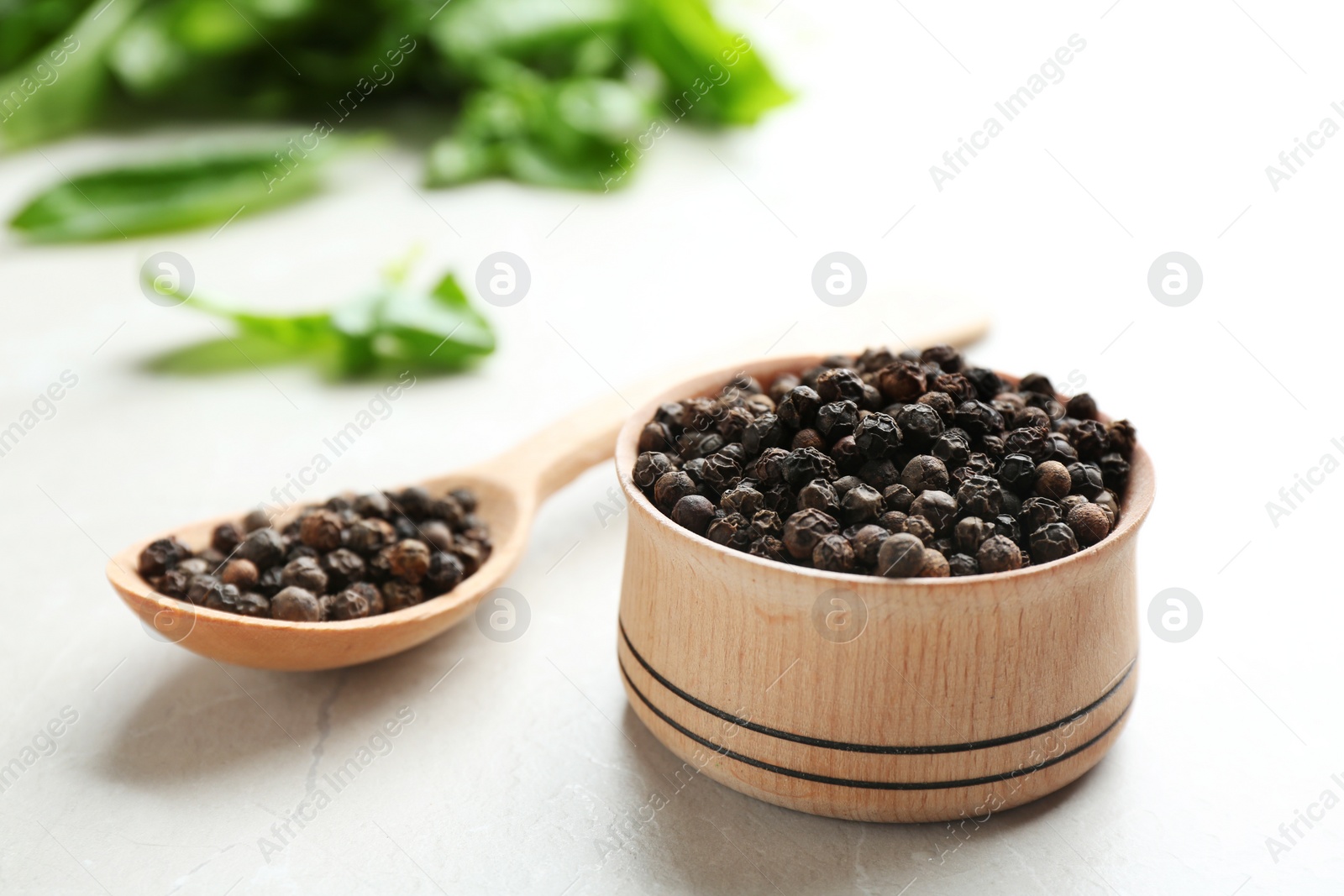 Photo of Bowl and spoon with black peppercorns on marble table