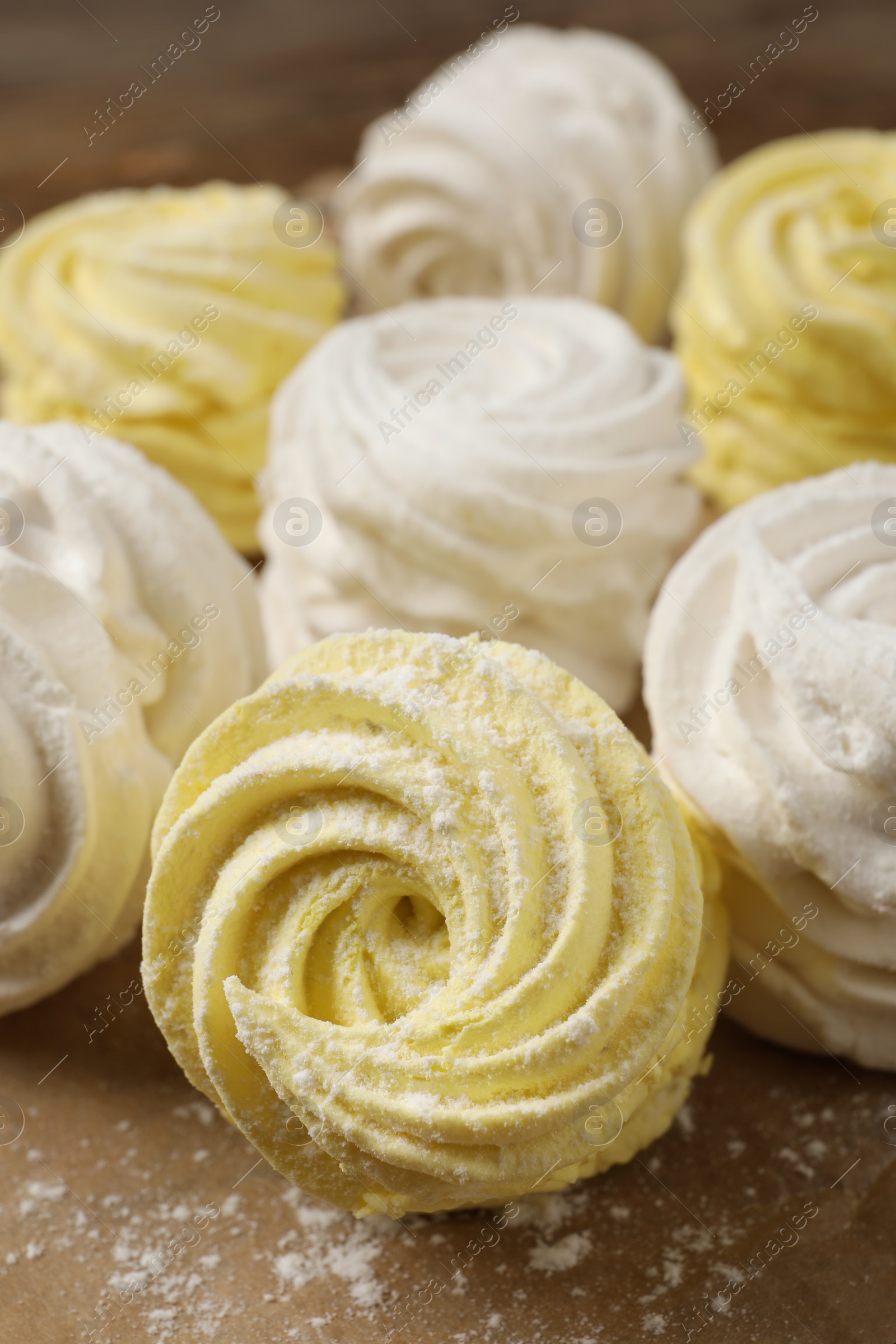 Photo of Delicious white and yellow marshmallows on parchment paper, closeup