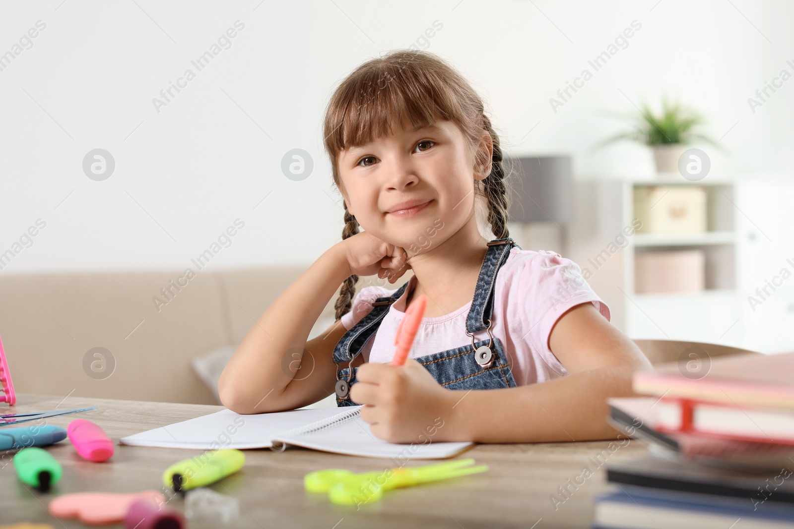 Photo of Little girl doing assignment at home. Stationery for school