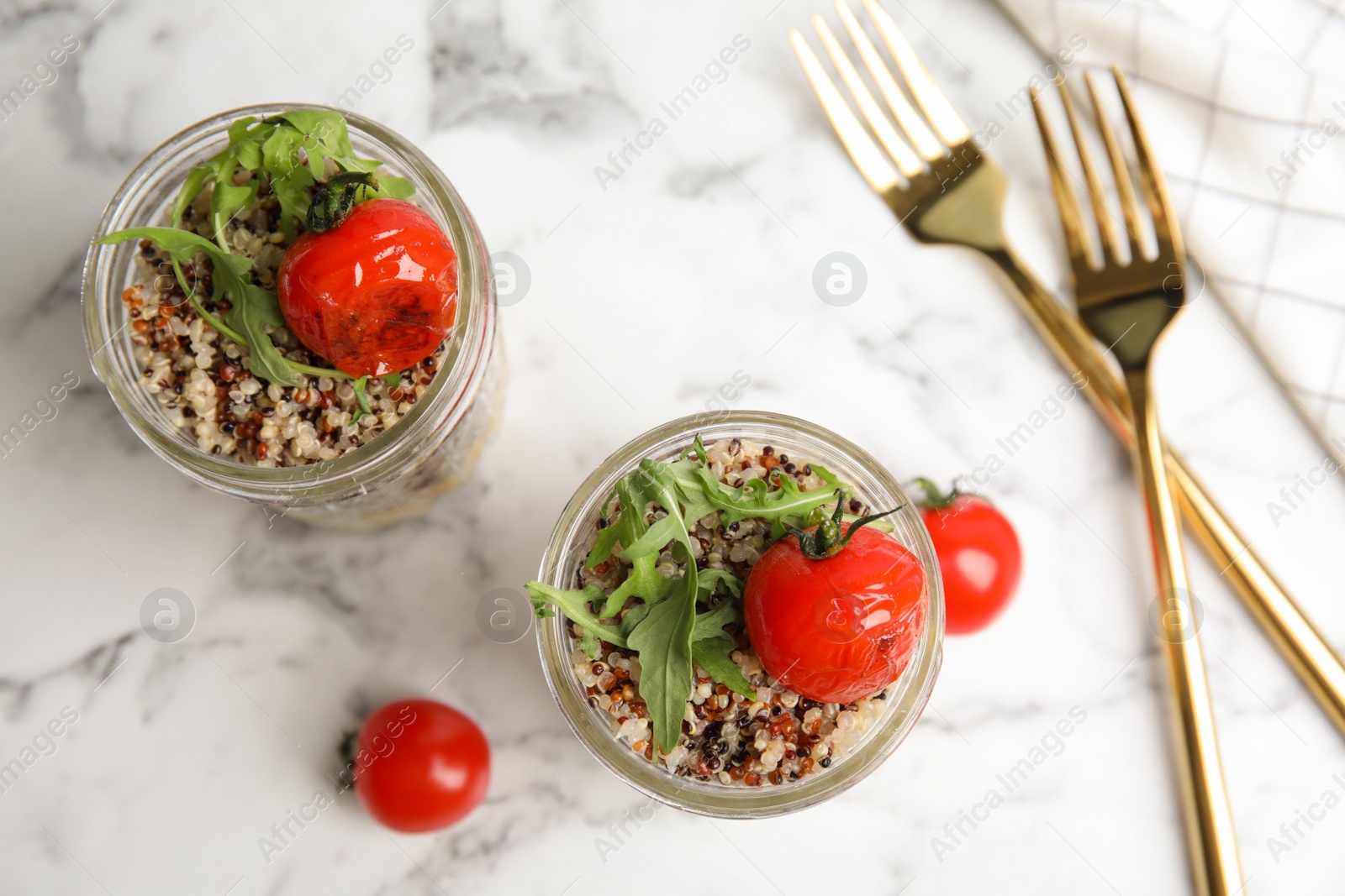 Photo of Healthy quinoa salad with vegetables in jars and forks on table, top view