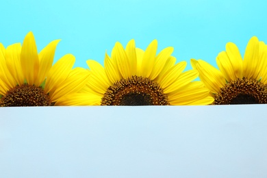 Photo of Beautiful bright sunflowers and card on color background