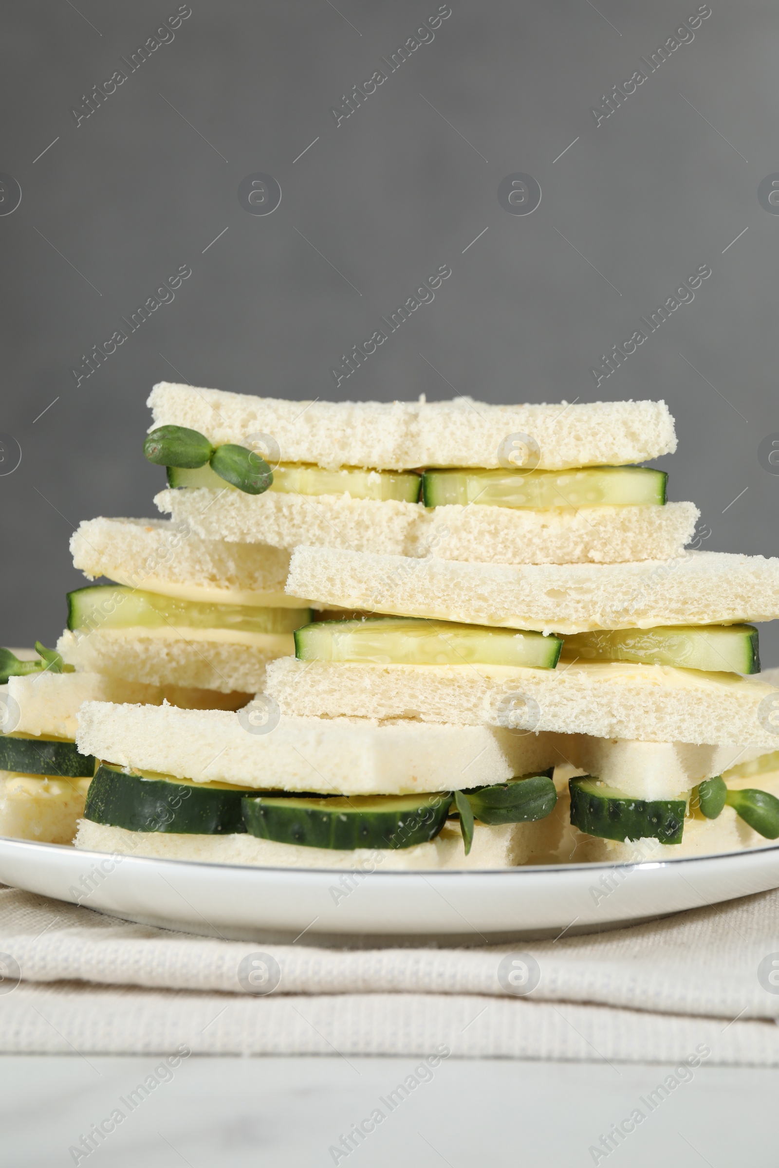 Photo of Tasty sandwiches with cucumber, butter and microgreens on white table