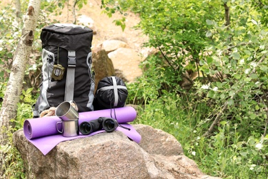 Photo of Backpack and camping equipment on stone in forest. Space for text
