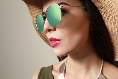Photo of Beautiful woman in stylish sunglasses and hat on beige background