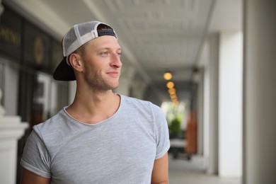 Photo of Handsome young man in stylish cap indoors, space for text