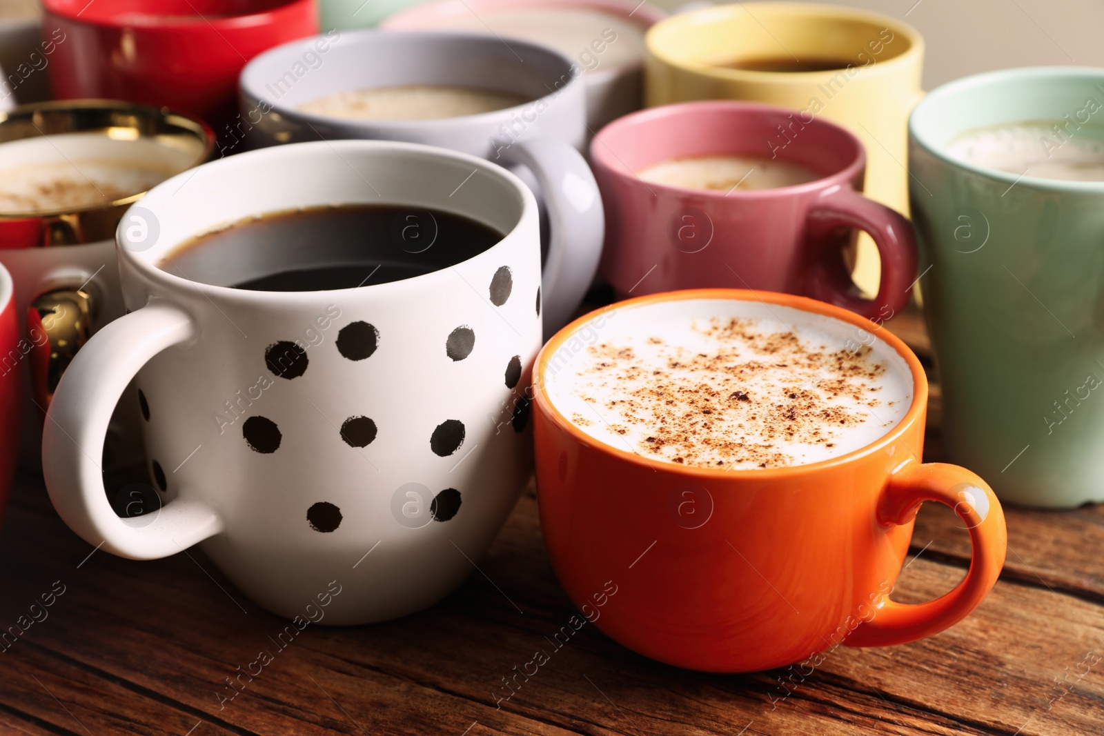 Photo of Many cups of different coffees on wooden table, closeup