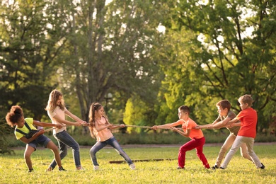 Photo of Cute little children playing with rope outdoors on sunny day