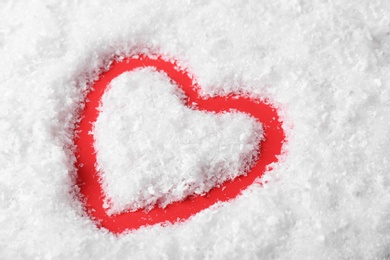 Photo of Heart shaped silhouette in decorative snow on color background
