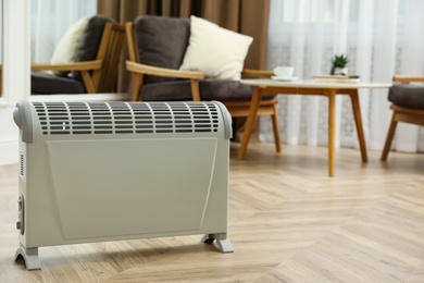 Photo of Modern electric convection heater on floor at home. Space for text